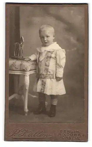 Fotografie P. Zallow, Berlin-Rixdorf, Bergstr. 140, Kleines Kind im Kleid mit Spielzeugpferd