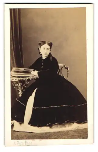 Fotografie A. Ken, Paris, junge Frau im schwarzen Kleid mit weissen Unterkleid und Ohrringen