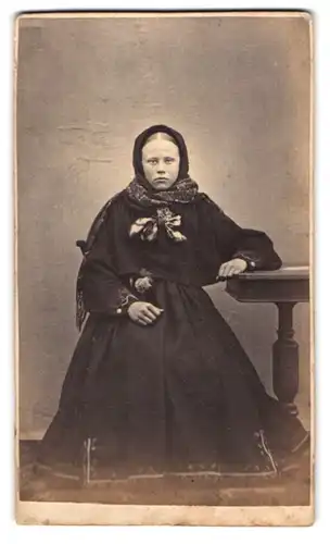 Fotografie unbekannter Fotograf und Ort, junges Mädchen im schwarzen Winterkleid mit Kopftuch und Schal