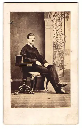 Fotografie London & Provincial Photog. Co., London, junger englischer Herr im Anzug nebst Zylinder auf dem Tisch