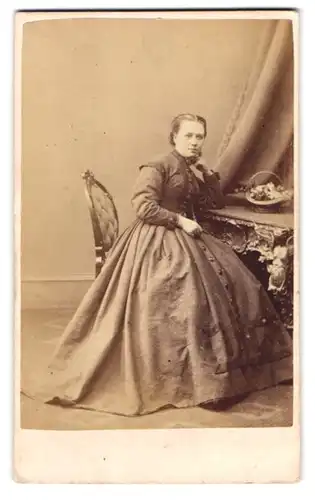 Fotografie unbekannter Fotograf und Ort, junge Dame im Kleid posiert sitzend am Schreibtisch