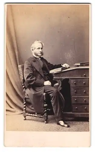 Fotografie London Stereoscopic Co., London, älterer Herr im Anzug mit Backenbart sitzend am Sekretär