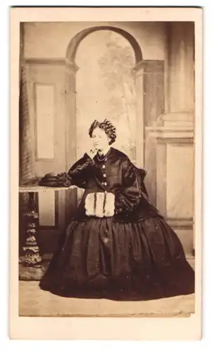 Fotografie Henry Jackson, Fishguard, junge Waliserin im dunklen Winterkleid mit Muff vor einer Studiokulisse