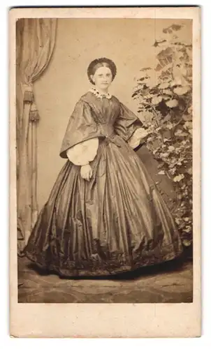 Fotografie F. Wolfram, Dresden, junge Frau im seidenen Kleid mit Haube, Studiokulisse