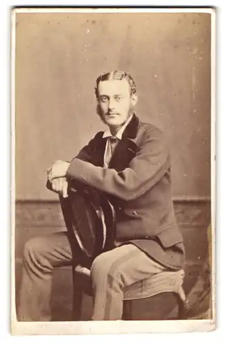 Fotografie A. & E. Seeley, London-Richmond, junger Mann im Anzug sitzt verkehrt herum auf dem Stuhl