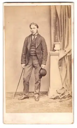 Fotografie unbekannter Fotograf und Ort, junger Mann im Anzug mit Flanierstock und Hut, Koteletten