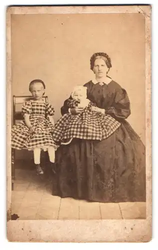 Fotografie unbekannter Fotograf und Ort, Mutter im dunklen Kleid mit ihren beiden Töchter in karierten Kleidern