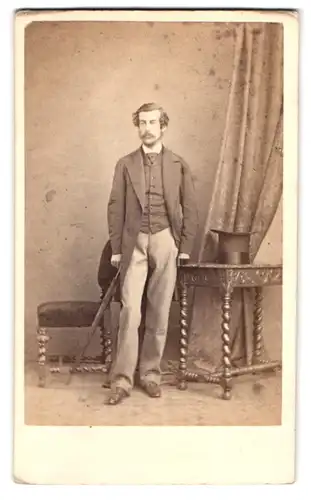 Fotografie Schnadhorst, London, englischer Herr im Anzug mit Flanierstock und Zylinder auf dem Tisch