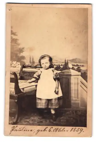 Fotografie unbekannter Fotograf und Ort, niedliches kleines Mädchen Pauline im Kleid vor einer Studiokulisse