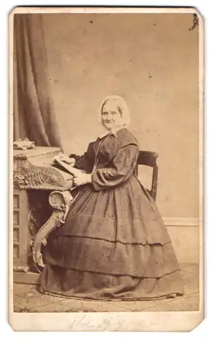 Fotografie W. Dalrymple Thomson, London, ältere Dame im reifrock Kleid mit Haube am Sekretär sitzend