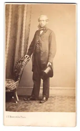 Fotografie C. T. Newcombe, London, Herr im Anzug mit Backenbart und Zylinder in der Hand