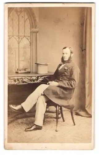 Fotografie Gush & Ferguson, London, englischer Herr im Anzug mit Backenbart und hellem Zylinder auf dem Tisch