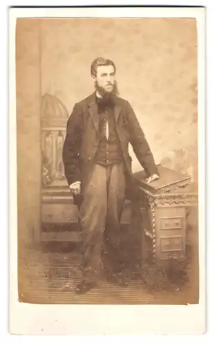 Fotografie J. Mitchell, Truro, Herr im dunklen Anzug mit Vollbart vor einer Studiokulisse