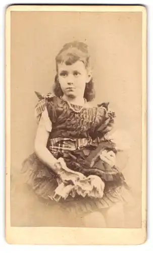 Fotografie unbekannter Fotograf und Ort, junges Mädchen im schicken Kleid mit Puppe in der Hand, 1879