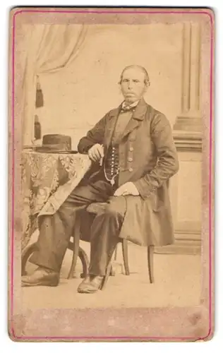 Fotografie J. X. Knoll, Wiggensbach, älterer Mann im Anzug mit Hut auf dem Tisch