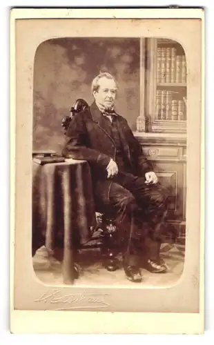 Fotografie John Eastham, Mancherster, ältere Herr im Anzug sitzend in einer Studiokulisse