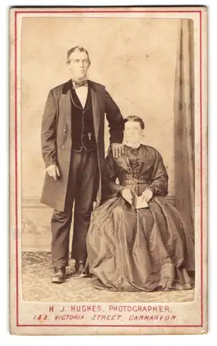 Fotografie H. J. Hughes, Carnarvon, Waliser Paar im Kleid und im Anzug mit Kinnbart