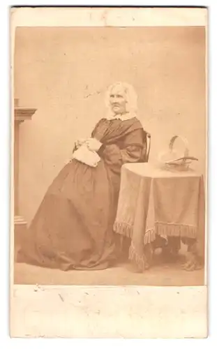 Fotografie Bannister, Carlisle, ältere Dame im dunklen Kleid mit Haube beim Stricken