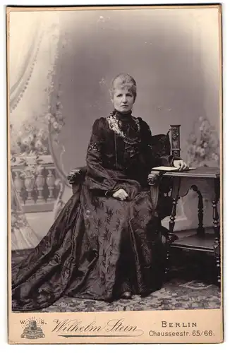 Fotografie Wilhelm Stein, Berlin, Chausseestr. 65-66, Elegante Dame mit Buch am Tisch