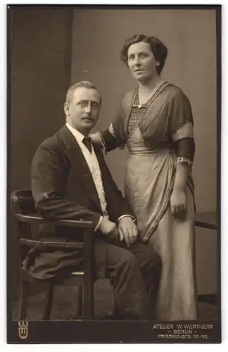 Fotografie W. Wertheim, Berlin, Friedrichstr. 110-112, Bürgerliches Paar an einem Stuhl