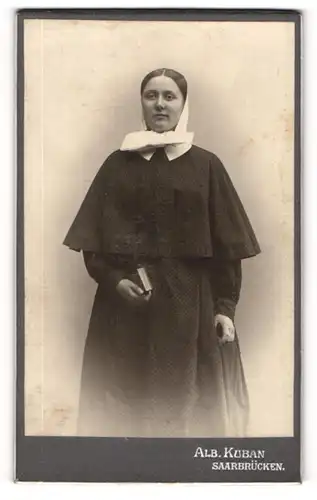 Fotografie Alb. Kuban, Saarbrücken, Portrait junge Dame in Uniform einer evangelischen Diakonisse mit Kopftuch und Buch