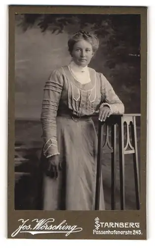 Fotografie Jos. Wörsching, Starnberg, Portrait modisch gekleidete Dame mit Flechtfrisur an Tisch gelehnt