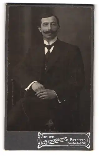 Fotografie H. Flasskämper, Bielefeld, Portrait sitzender Herr im Anzug mit Krawatte und Schnauzbart
