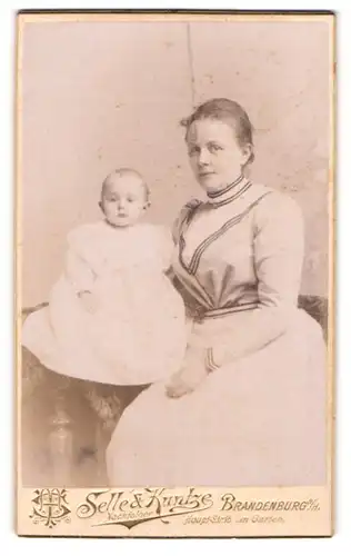 Fotografie A. Tietz & H. Schweitzer, Brandenburg a / H., Portrait sitzende Dame im modischen Kleid mit Baby im Arm