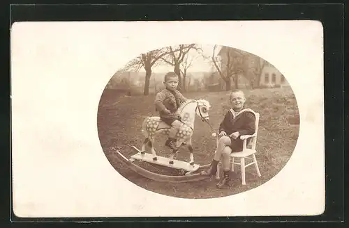 Foto-AK Zwei kleine Jungen mit einem Schaukelpferd im Freien