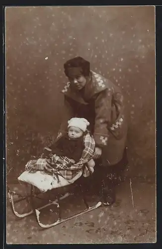 Foto-AK Kleinkind auf Schlitten neben Mutter