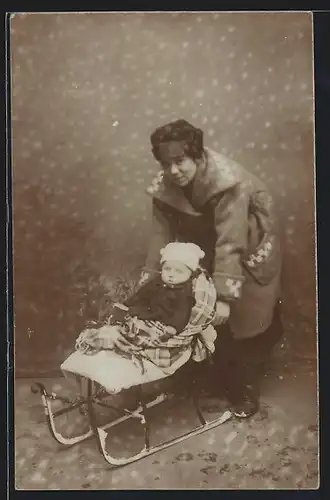 Foto-AK Kleinkind auf Schlitten neben Mutter