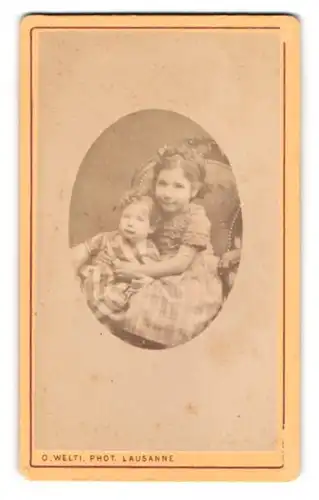Fotografie O. Welti, Lausanne, Portrait kleines Mädchen im karierten Kleid mit Kleinkind auf dem Schoss