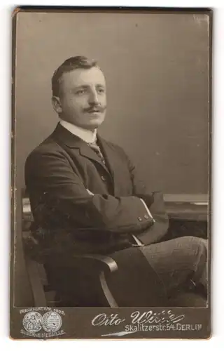 Fotografie Otto Witte, Berlin, Portrait sitzender Herr in Anzugjacke mit verschränkten Armen