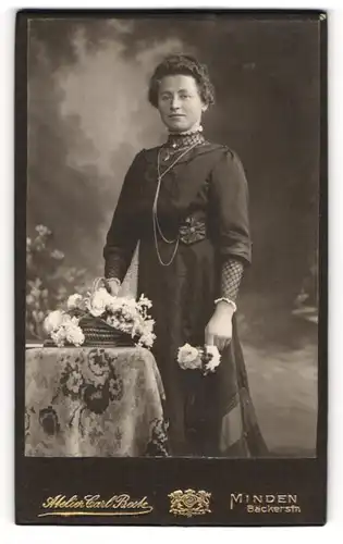 Fotografie Carl Beste, Minden, Portrait bürgerliche Dame mit Blume an Tisch gelehnt