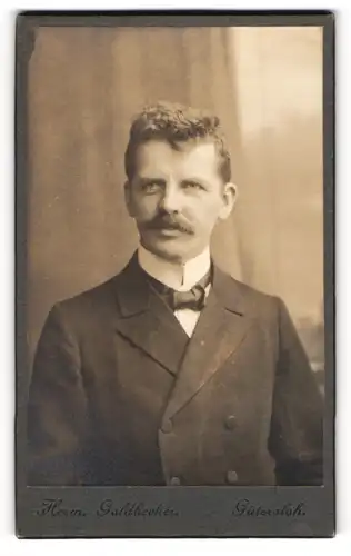 Fotografie Herm. Goldbecker, Gütersloh, Portrait junger Herr im Anzug mit Fliege und Schnurrbart