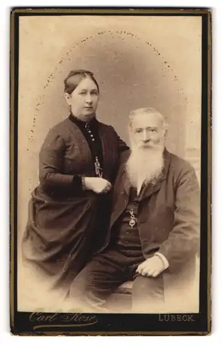 Fotografie Carl Rose, Lübeck, Portrait älterer Herr in schlichter Kleidung mit weissem Bart und Frau