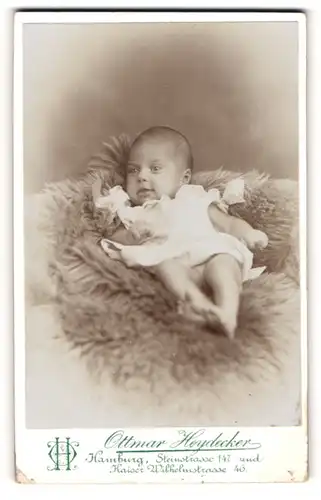 Fotografie Ottmar Heydecker, Hamburg, Portrait süsses Baby im weissen Hemd auf Fell liegend