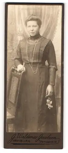 Fotografie J. Waldemar Jacobsen, Hamburg, Dame in dunklem Kleid trägt Halskette und hält einen Blumenstrass