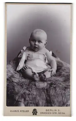 Fotografie Globus Atelier, Berlin, niedliches Baby auf Felldecke sitzend