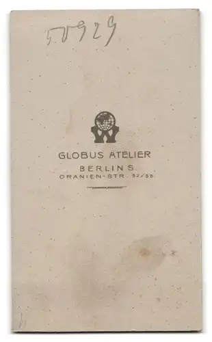 Fotografie Globus Atelier, Berlin, Baby im weissen Kleidchen auf Felldecke sitzend