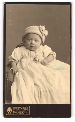 Fotografie Wertheim, Berlin, Portrait Säugling in Kleid mit Mütze