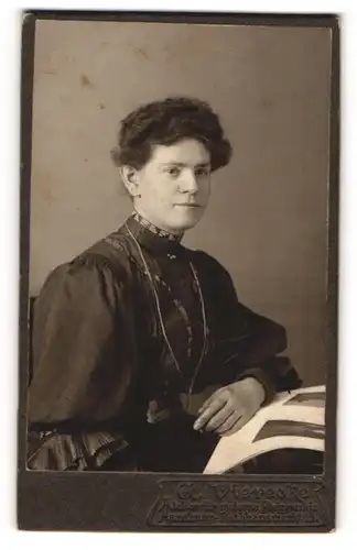 Fotografie G. Vierecke, Hamburg, Portrait hübsch gekleidete Dame mit Zeitung am Tisch sitzend