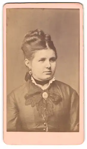 Fotografie H. A. Krull, Neu-Strelitz, junge Dame im dunklen Kleid mit Brosche und hochgesteckten Haaren