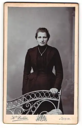 Fotografie H. Bichler, Steyr, Bahnhofstr., Junge Dame in schwarzem taillertem Kleid mit langer Silberkette und Ring