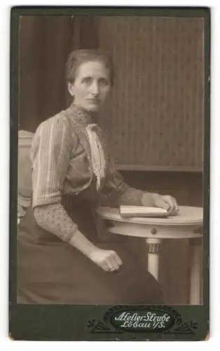 Fotografie Woldemar Strube, Löbau i. S., Junge Dame in hellem Kleid und schwarzem Rock mit Perlenkette und Buch