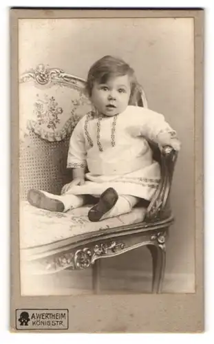 Fotografie A. Wertheim, Berlin, Portrait süsses Kleinkind im hübschen Kleid auf Bank sitzend