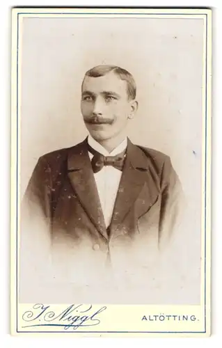 Fotografie J. Niggl, Altötting, Portrait junger Herr im Anzug mit Fliege und Schnurrbart