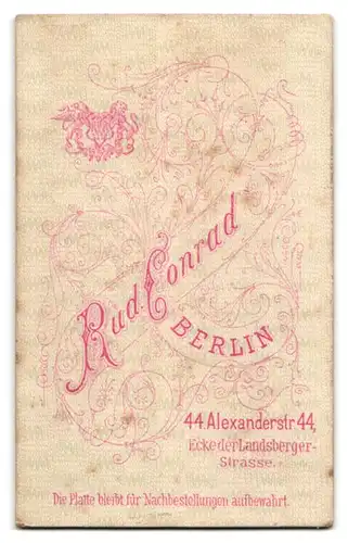 Fotografie Rud. Conrad, Berlin, Alexanderstrasse 44, Dame mit ernstem Blick und Flechtfrisur, Brosche und Kette