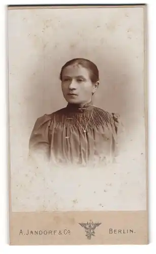 Fotografie A. Jandorf & Co., Berlin, Spittelmarkt 16, Junge Frau in dunklem Kleid mit glatten Gesichtszügen und Kette