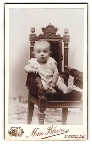 Fotografie Max Blum, Meerane, Portrait sitzendes Kleinkind im weissen Hemd mit nackigen Füssen